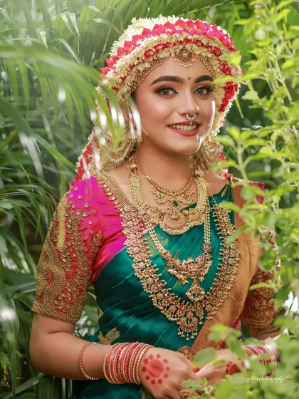 A beautiful portrait framed by greenery, highlighting the contrast between the green saree and the pink flowers in the Sharadha Jalli.