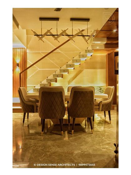 This dining area is defined by the stunning modern staircase behind it. The design uses clean lines, integrated lighting, and plush quilted chairs to create a sophisticated space for family meals.