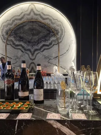 An elegant and modern bar setup featuring a striking marble backdrop. The display includes premium wines, spirits, and gourmet appetizers, creating a sophisticated station for guests to enjoy.