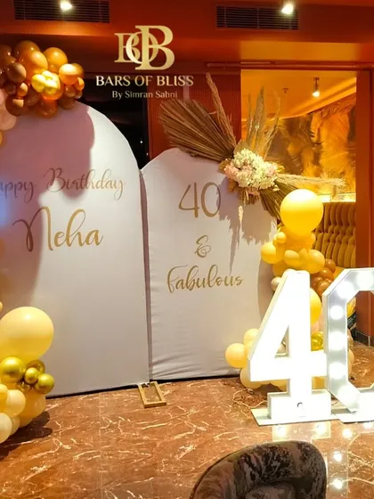A wider view of the '40 & Fabulous' birthday setup, showing how the dual arched backdrops and balloon arrangements come together to create a cohesive and impressive photo zone for the event.