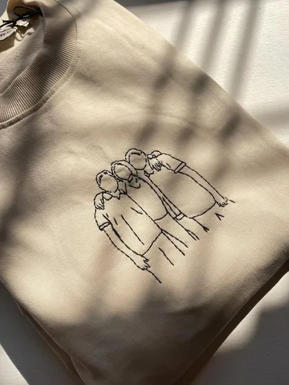 The texture of the thread against the fabric. This close-up shows the detail of the hand-stitched line art portrait.