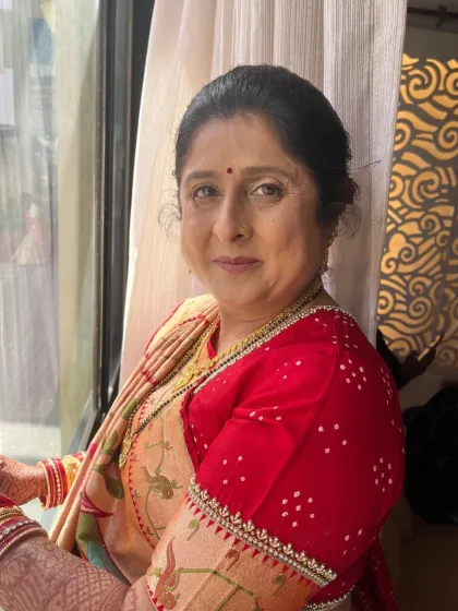 A beautiful, soft-lit portrait of the groom's mom. Her makeup is natural and radiant, highlighting her warm smile.