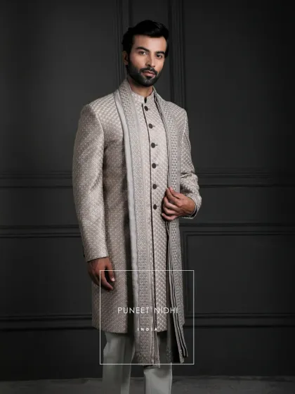 A closer look at the soft champagne jacquard sherwani. The clean lines, looped buttons, and mandarin collar are finished with a matching stole for a modern yet timeless look.