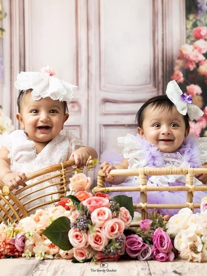 Double the smiles. Two adorable twin babies in their baskets, surrounded by a sea of colorful flowers.