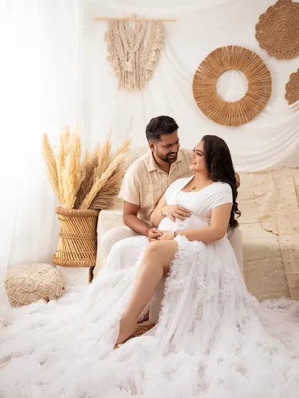 The connection between them is beautifully captured as they gaze at each other. The boho setup provides a warm and intimate backdrop.