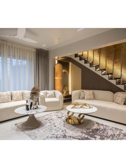 The living room of the Duplex Project, featuring a stunning staircase with gold-finished paneling. This element adds a touch of glamour and reflects light beautifully, enhancing the sense of luxury.