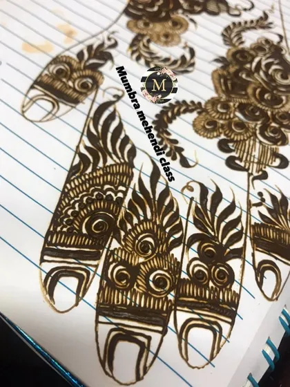 A close-up of finger designs on a practice sheet, focusing on leafy and swirling patterns.