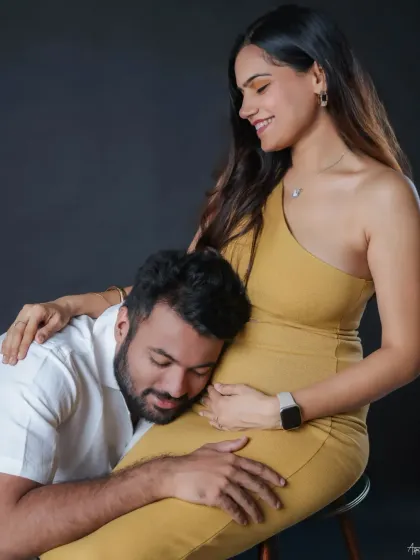 A tender moment where the father-to-be connects with his unborn child. The clean, dark background of the studio ensures that nothing distracts from this simple, emotional interaction.