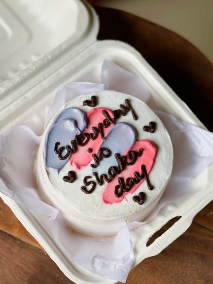 A motivational and fun bento cake with the message "Everyday is Shaka day." The colorful pink and purple brushstrokes add a splash of energy to the design.