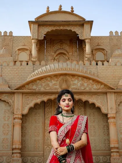 A full-shot of the bride standing before an ornate, architectural set. This kind of portrait showcases the grandeur of the wedding day.