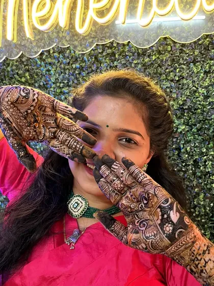 The bride showing off her intricate mehendi design. The green backdrop with the neon sign makes for a very trendy photo.