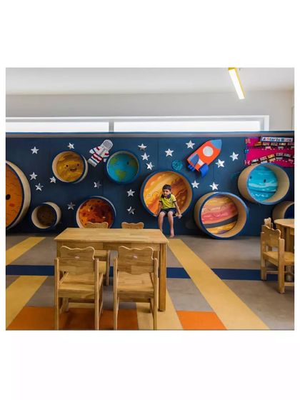 The 'planet wall' in the 'Toy Story' preschool is an interactive feature with circular nooks for children to sit and play in, combining learning with physical engagement.