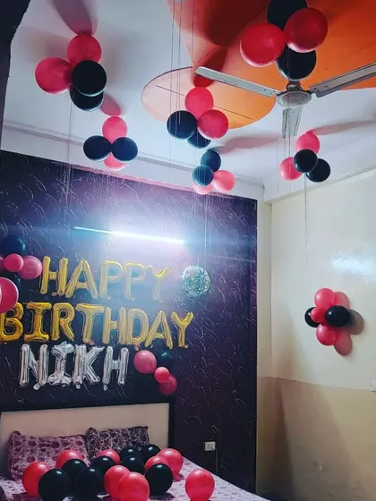 A wider view of the red and black birthday decor, showing how the balloon clusters are arranged across the ceiling to fill the space.