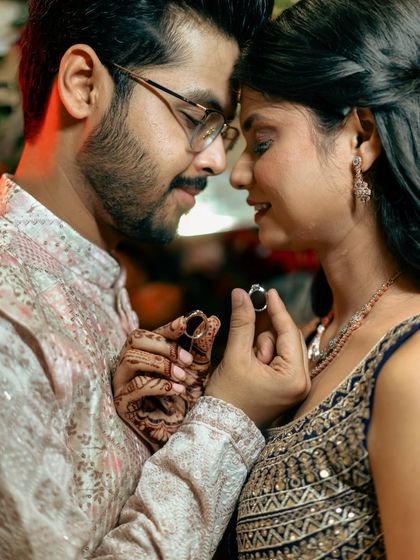 An intimate close-up of the couple holding their engagement rings, their faces close in a moment of quiet connection.