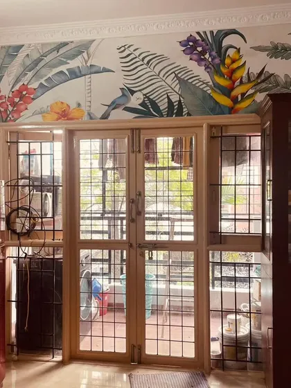 I often use murals to frame architectural features. Here, a colorful tropical flower and bird wallpaper is installed above a set of doors, adding a splash of color and life to the top of the wall.