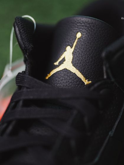 A close-up of the iconic Jumpman logo, embroidered in gold on the tongue of the J Balvin Jordan 3.