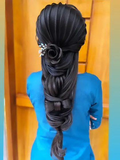 Showcasing advanced sculptural hair art, this style features a rose and a bow crafted entirely from hair. This unique and intricate braid is for the bride who wants a truly one of a kind look.