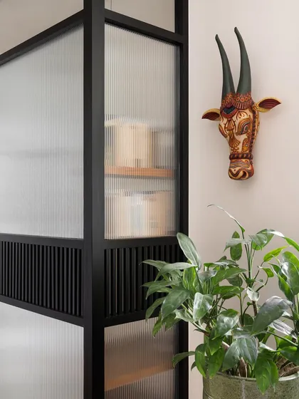 This detail of a study pod partition shows the combination of fluted glass and black metal framing. The addition of a traditional Indian cow head sculpture adds a personal and cultural touch.