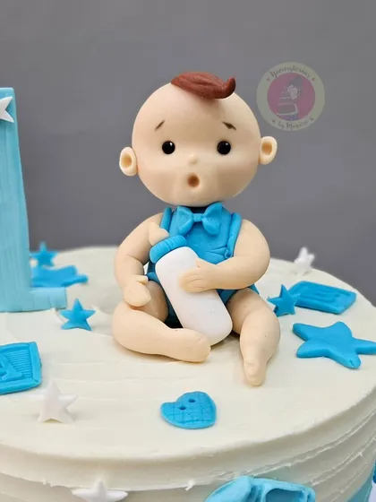 A simple and cute first birthday cake featuring an adorable baby boy figurine. Sometimes, the most heartwarming cakes are the ones with a clean design and one perfect, central character.