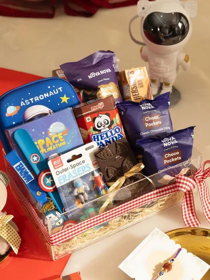 Our space-themed Rakhi hamper is perfect for a little brother. It includes an astronaut stationery box, colouring book, themed erasers, and plenty of yummy snacks.