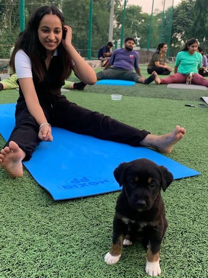 A participant smiles, sitting next to a tiny, adorable black puppy who is posing perfectly for the camera.