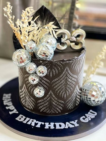 Turning 33 with glitz and glam! This black and silver disco-themed cake features a stunning pattern, shimmering disco balls, and dried floral accents for a truly celebratory vibe.
