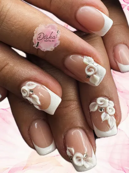 The perfect white wedding nails. This elegant set features a classic French manicure base, elevated with intricate 3D flowers and delicate crystal accents.