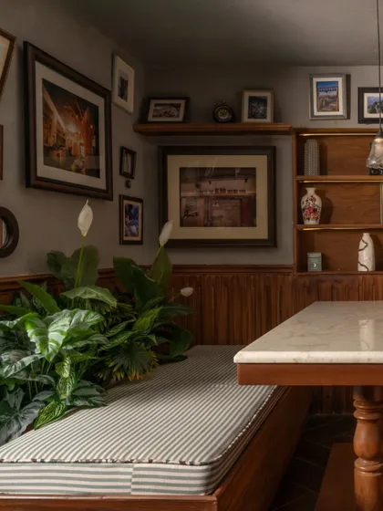 Another angle of the booth, where lush peace lilies soften the corner and add a touch of nature. The design balances rustic materials with comfortable furnishings to create a welcoming and restorative space.