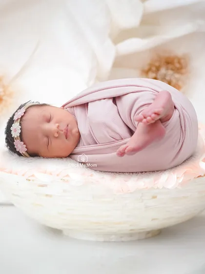 Curled up in a classic newborn pose, this baby girl is swaddled in dusty pink and resting in a beautiful marble-textured bowl.