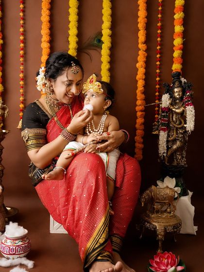 A sweet, interactive moment where the mother feeds her little Krishna a bit of cotton "butter."