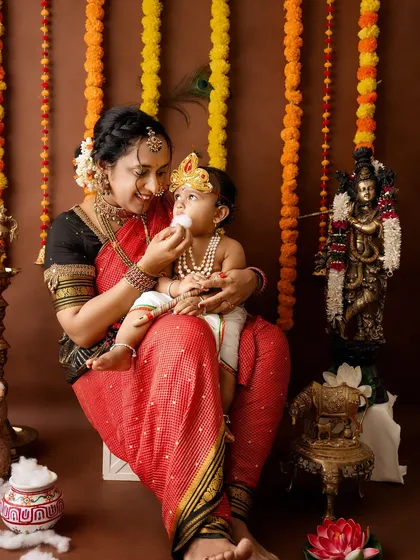 A sweet, interactive moment where the mother feeds her little Krishna a bit of cotton "butter."