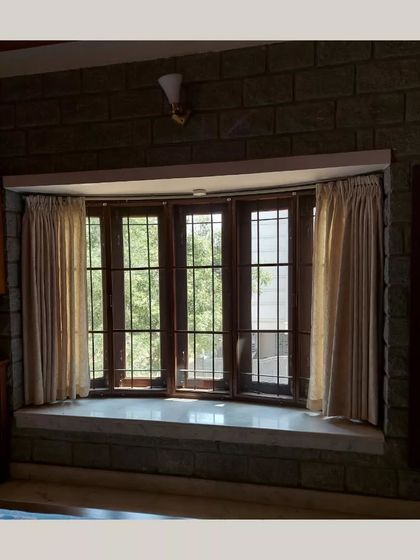 A bay window with a built-in seat, framed by a rugged stone wall, creating a cozy and well-lit reading nook.