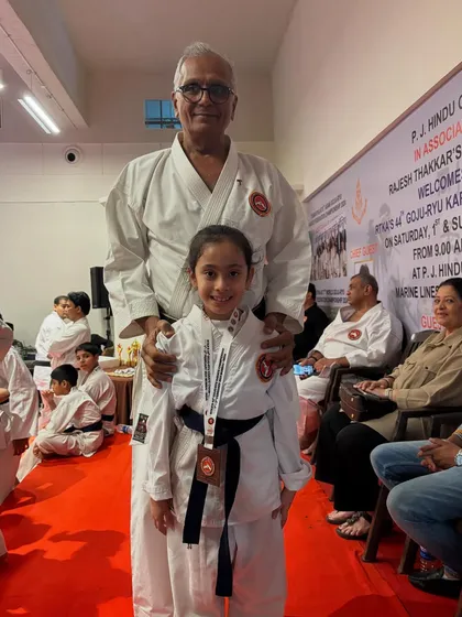 A young girl stands proudly with Kyoshi Sensei after winning a medal at our tournament. These moments of recognition are crucial for building confidence in our young students.