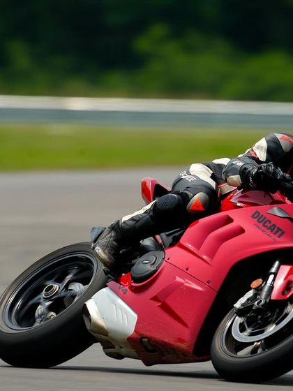 The sleek lines of a red Ducati Panigale V4 are on full display as it carves through a corner at Madras International Circuit.