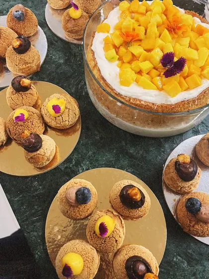 A mango tres leches sharing the table with plates of assorted choux pastries. This shows the variety of desserts you can order for your special occasions.