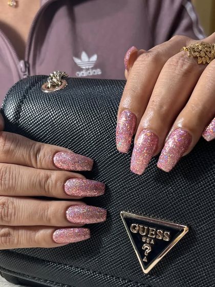 A full set of beautiful pink glitter nail extensions. The coffin shape is modern, and the holographic glitter adds incredible sparkle and dimension.