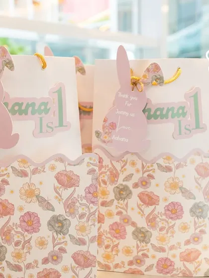 Custom floral-print gift bags with personalized bunny tags, filled with goodies for Aahana's little guests.