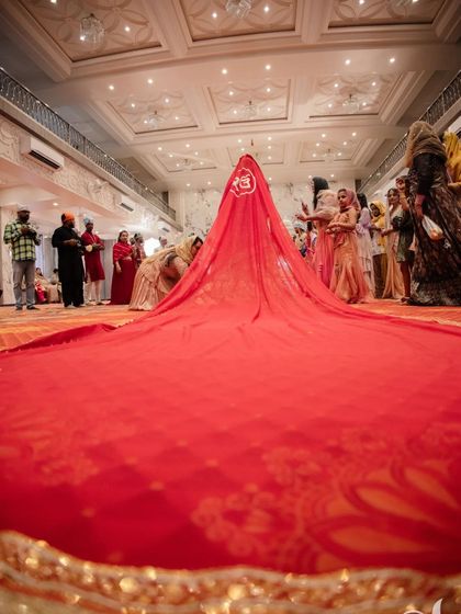 The bride's dramatic entrance at the Gurudwara, her long red veil trailing behind her, creating a breathtaking image.