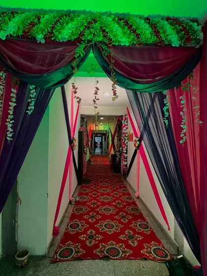 A grand entrance for a hallway, using a combination of green, pink, and black drapes with floral bunches.
