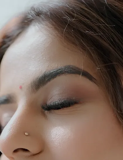 A macro shot of a soft, natural eye makeup look. The eyeshadow is subtly blended, and the brows are defined but not harsh, perfect for a "no-makeup" makeup style.