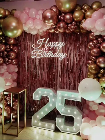 Celebrating a milestone like a 25th birthday calls for something special. We designed this chic setup with a rose gold sequin wall, a matching balloon arch, and large marquee numbers to make the occasion truly shine.