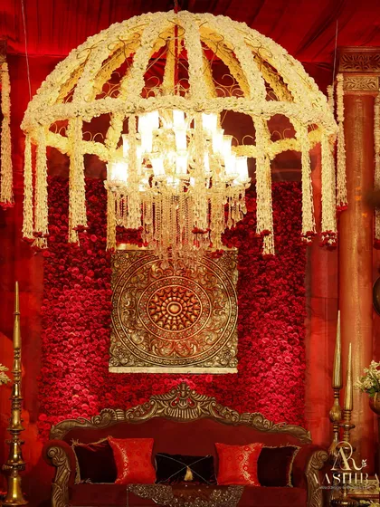 A close-up of the stage, where a wall of red roses and a traditional medallion were framed by a magnificent chandelier dressed in fragrant white tuberoses.