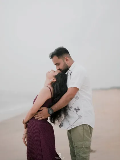 A romantic forehead kiss, a classic and timeless pose for any couple photoshoot. The soft focus on the waves adds to the dreamy atmosphere.