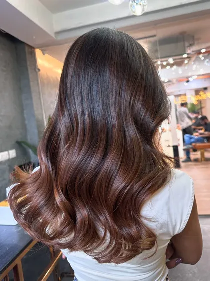 A warm-toned balayage with hints of copper and caramel. This color combination is perfect for adding warmth and richness to dark hair.