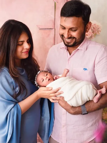A beautiful family portrait from one of our luxury newborn sessions. The parents hold their baby together against a stunning floral backdrop, creating a work of art.