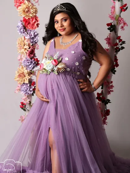 A stunning solo portrait on the floral swing. The vibrant flowers and the flowing purple gown create a beautiful, eye-catching image that celebrates motherhood.