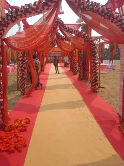 A long wedding walkway decorated with arches of red and white flowers and drapes, ready for the arrival of guests.