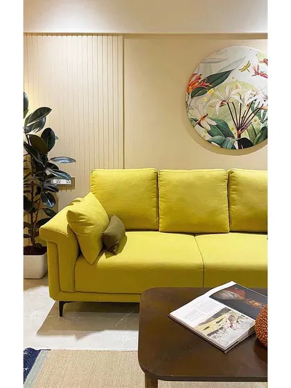A custom circular botanical artwork hangs above a vibrant yellow sofa, bringing a touch of nature and artistry into this indie-themed living room.