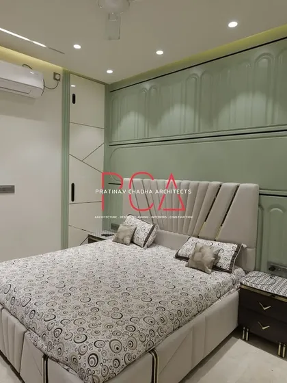 A view of the master bedroom in The Cursive Abode project, showcasing a bespoke design with intricate wall paneling and integrated lighting. The pastel green tones and fluted details create a serene yet sophisticated atmosphere, reflecting my ability to craft personalized and opulent living spaces.