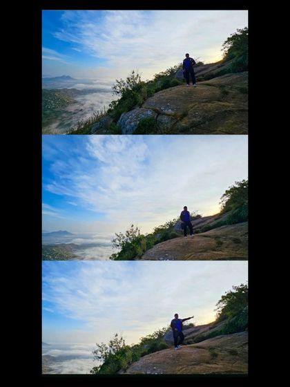 A trekker enjoying the vast, open landscape near the peak of Skandagiri, with a blanket of clouds covering the world below.